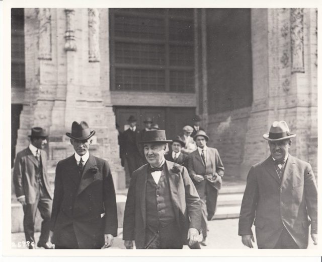 Thomas Edison and Henry Ford walking with a group outside a palace