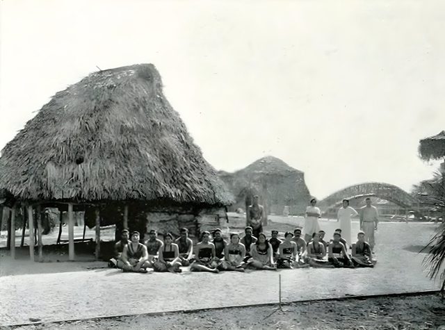 A grass-thatched Samoan house on the Zone, with the villagers who performed there