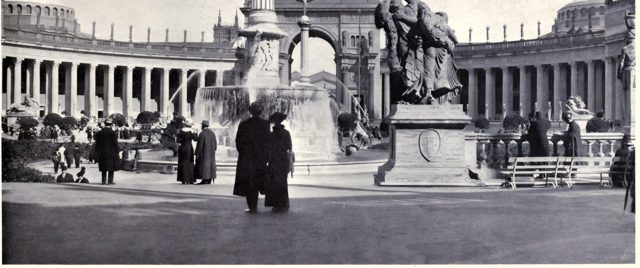 Visitors by a fountain in the Court of the Universe, the Arch of the Rising Sun behind